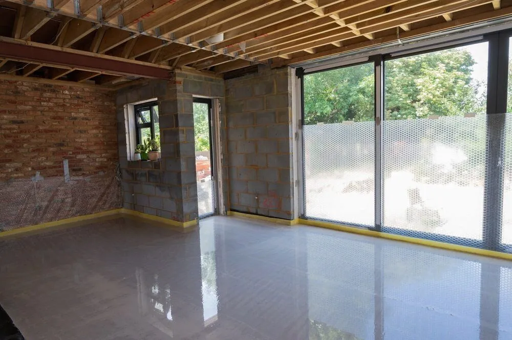 A Large Empty Room With a Lot of Windows and a Brick Wall — Ozi Construction Pty Ltd in Balmain, NSW