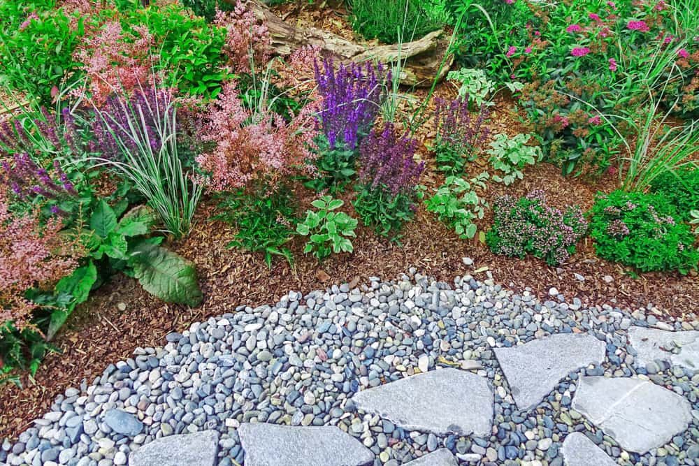 A Stone Walkway in a Garden Surrounded by Flowers and Plants — Ozi Construction Pty Ltd in Mosman, NSW