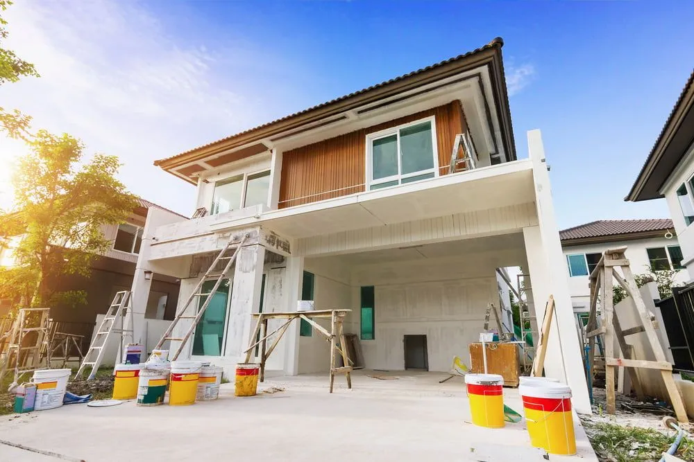 A House is Being Painted With Buckets of Paint in Front of It — Ozi Construction Pty Ltd in North Sydney, NSW