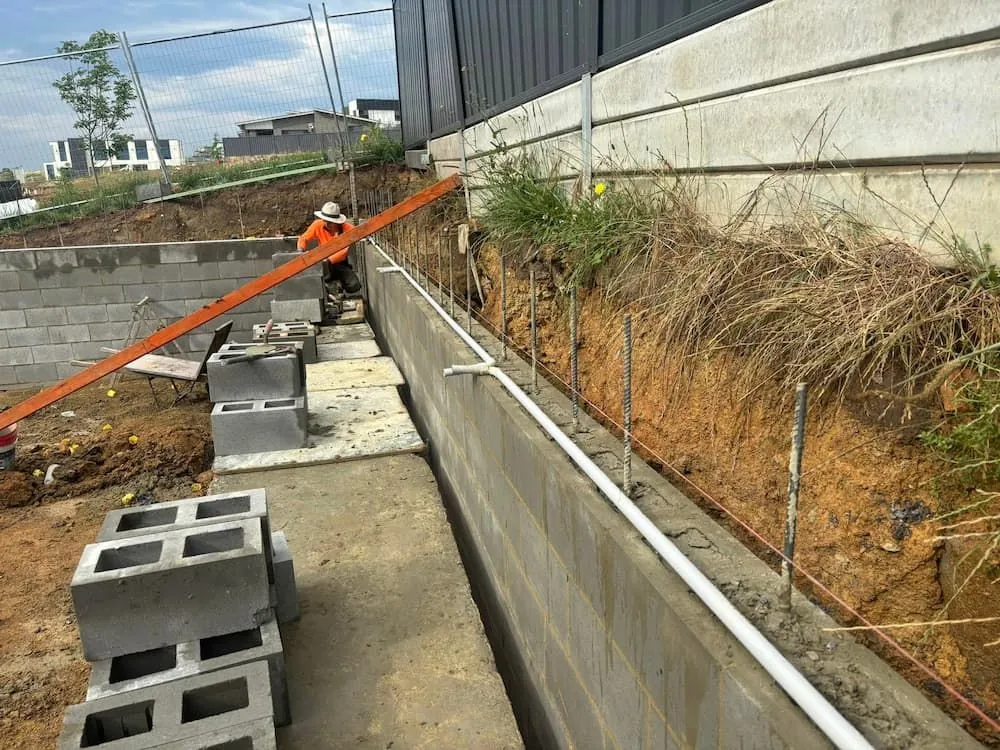 A Concrete Wall is Being Built With Bricks and Pipes — Ozi Construction Pty Ltd in North Sydney, NSW
