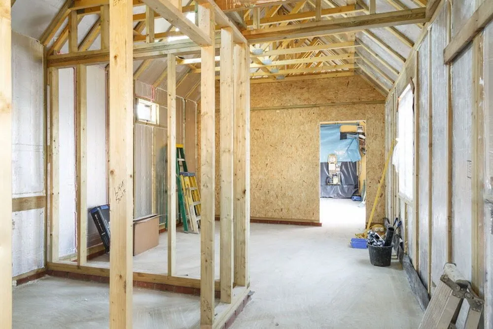 A Room Under Construction With Wooden Beams and a Ladder — Ozi Construction Pty Ltd in Sydney, NSW